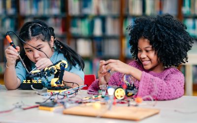 young girls building robotics project links to STEM and Academic Enrichment webpage